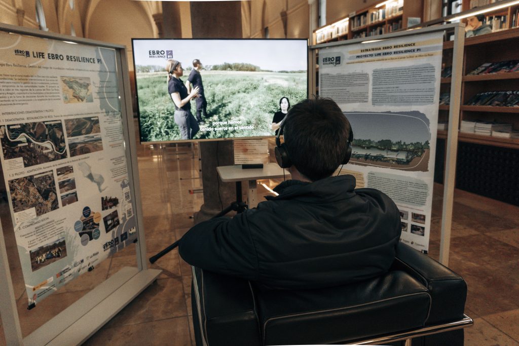 Exposición Cuando el río recupera su espacio. Punto de información audiovisual. Persona visionando los vídeos.